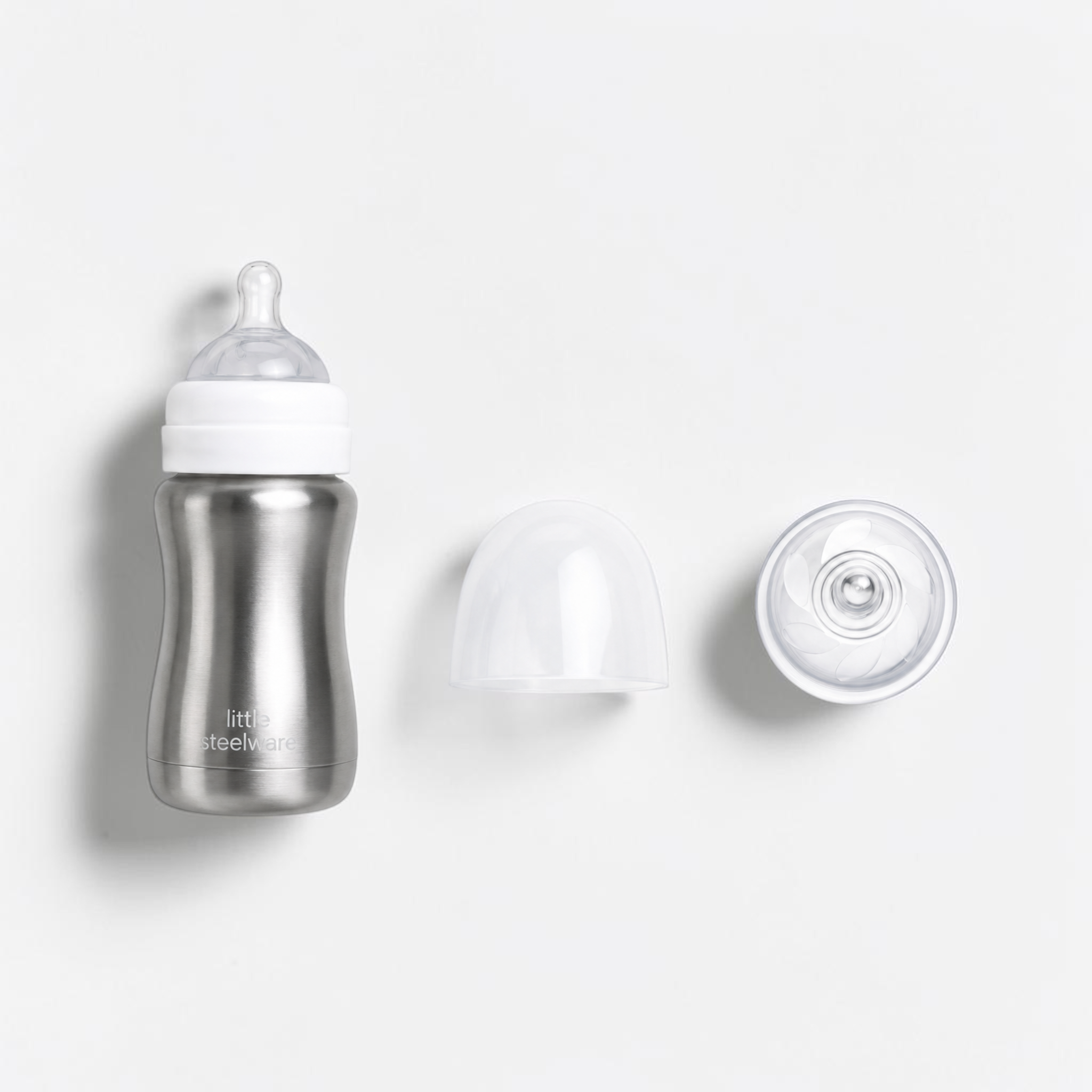 A stainless steel baby bottle with a white collar and clear silicone nipple, shown alongside a clear protective cap and a clear breast pump bulb on a clean white background. The brand name 'Little Steelware' is visible on the bottle.