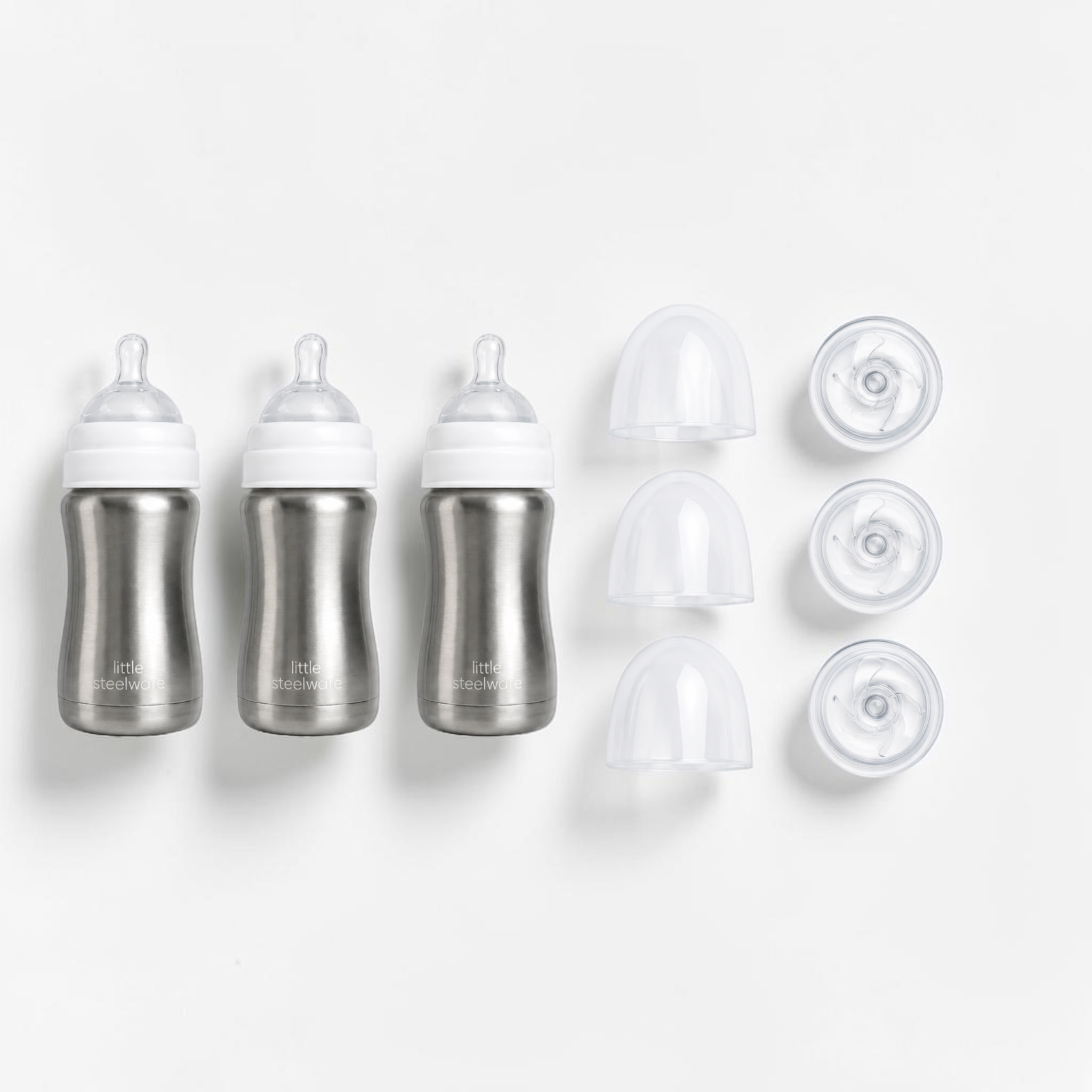Three stainless steel baby bottles with white caps and three clear accessories arranged on a clean white background.